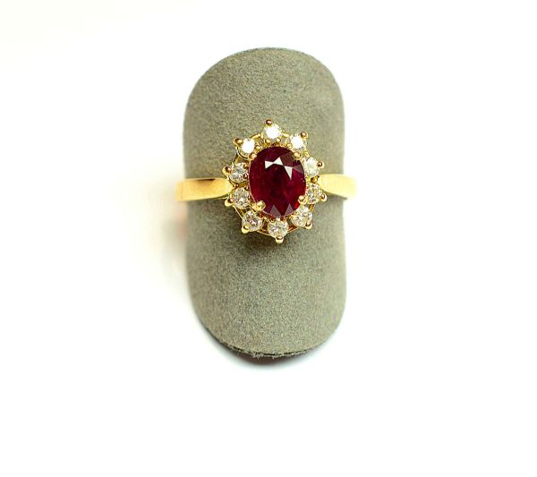 Bague en or jaune centrée d'un rubis ovale de belle couleur pour 1 c env dans un entourage de 10 diamants ronds taille brillant moderne. Or 2,96 g