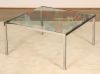 A coffee table in chromed metal and glass top