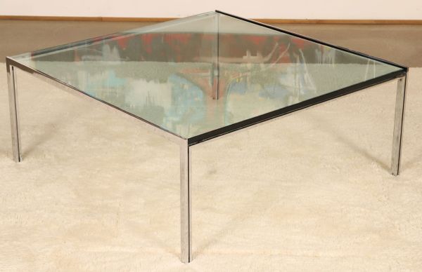 Une table basse en métal chromé et plateau de verre