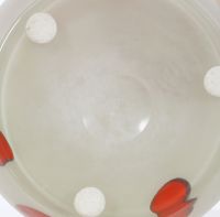 Milky-white glass vase with red pastilles in between. 