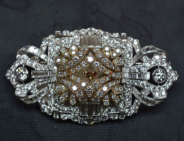 Important brooch in platinum and yellow gold set with some 300 diamonds, one of which is heart-cut in natural orange color, the whole for 27 c env quality F/G-VS. The importance of the size of the baguette diamonds is to be observed as well as a remarkable work of jewellery. Platinum and gold 49,34 g.