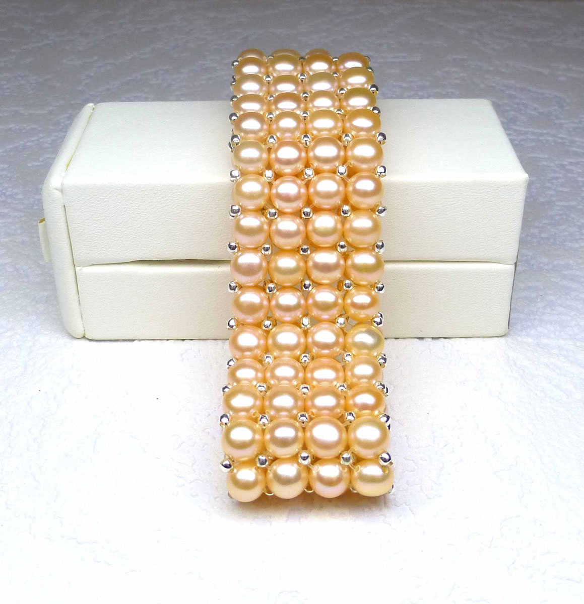 Bracelet with 4 rows of natural cultured pearls salmon color (D: 6 mm) mounted on elastic and decorated with silver patterns