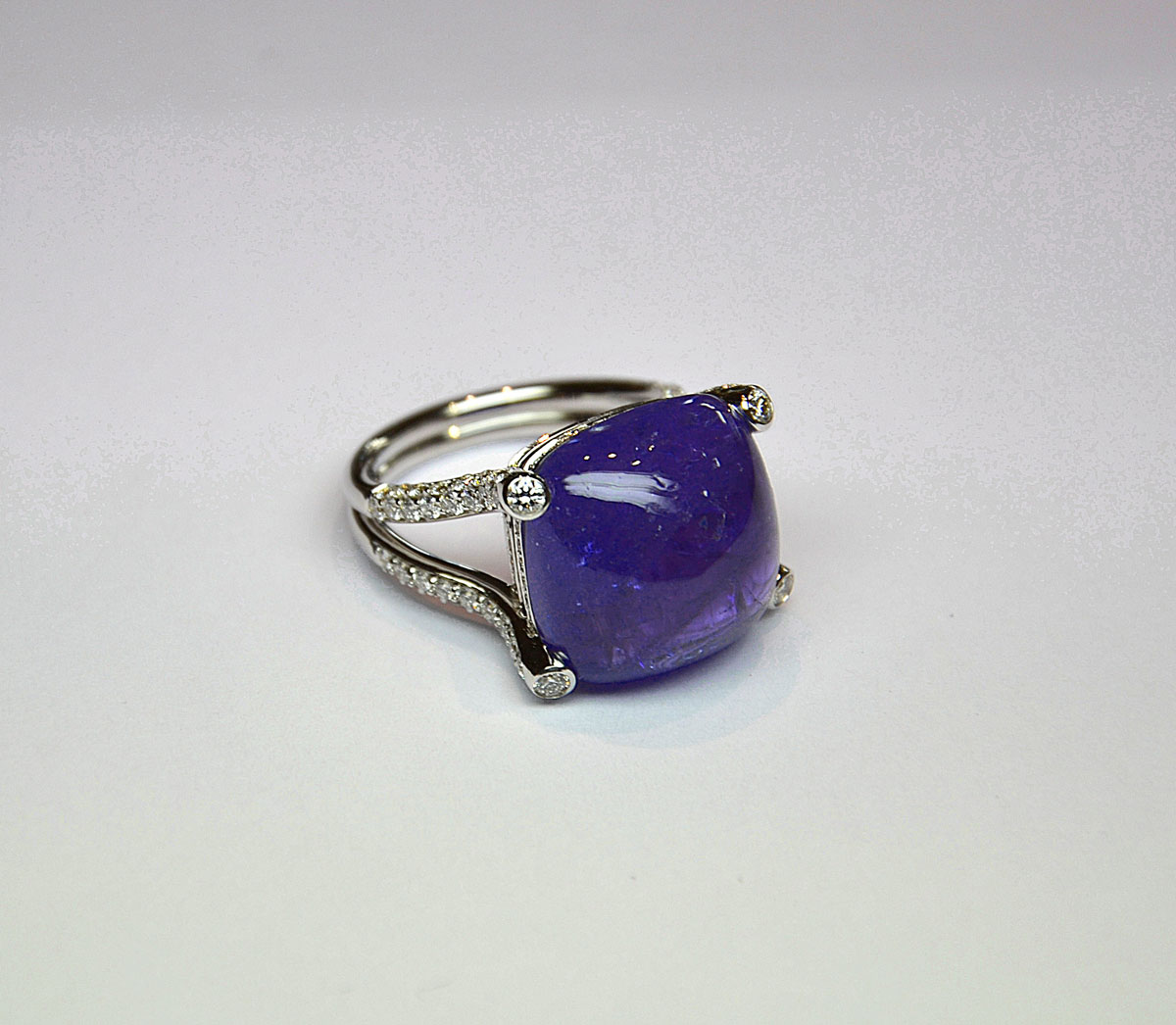 Bague en or blanc ornée d'une rare et importante tanzanite Naturelle taille coussin cabochon pour 24,54 c. Monture et griffes stylisées serties de diamants pour 1,40 c G/VS - Or 8,02 g. 